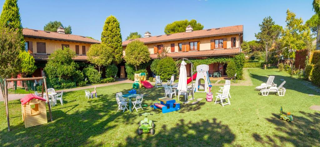 un patio con sillas y un parque infantil frente a una casa en Residence Borgo Stella Marina, en Bibione