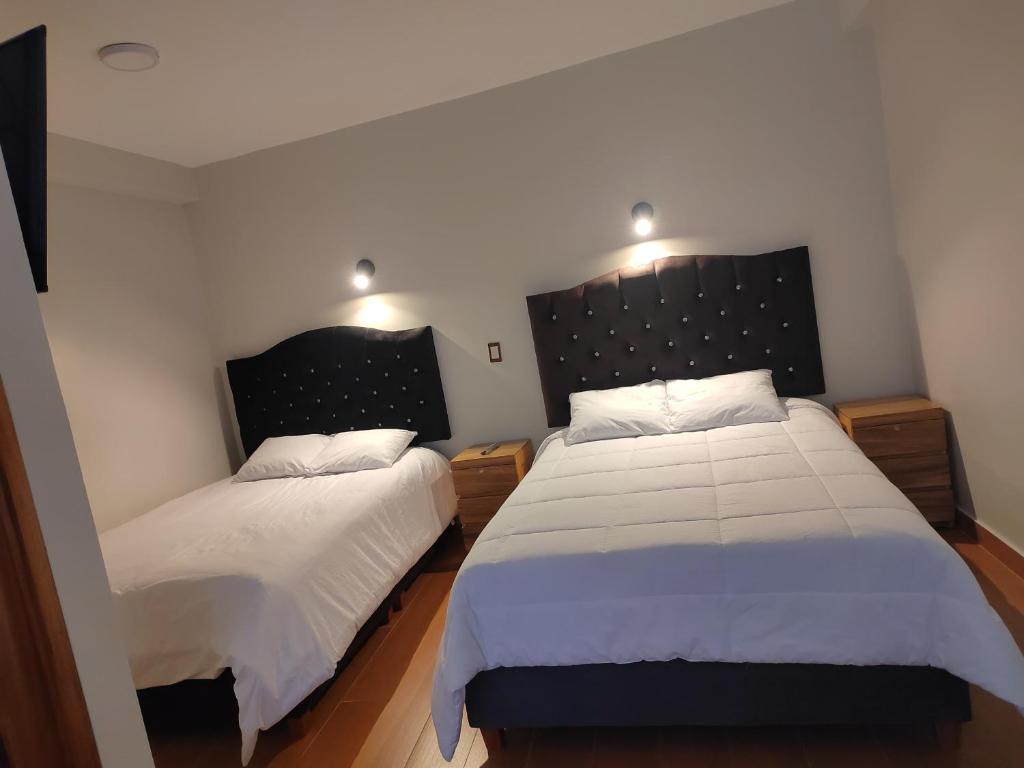 a bedroom with two beds with white sheets at Pumaexplorer in Urubamba
