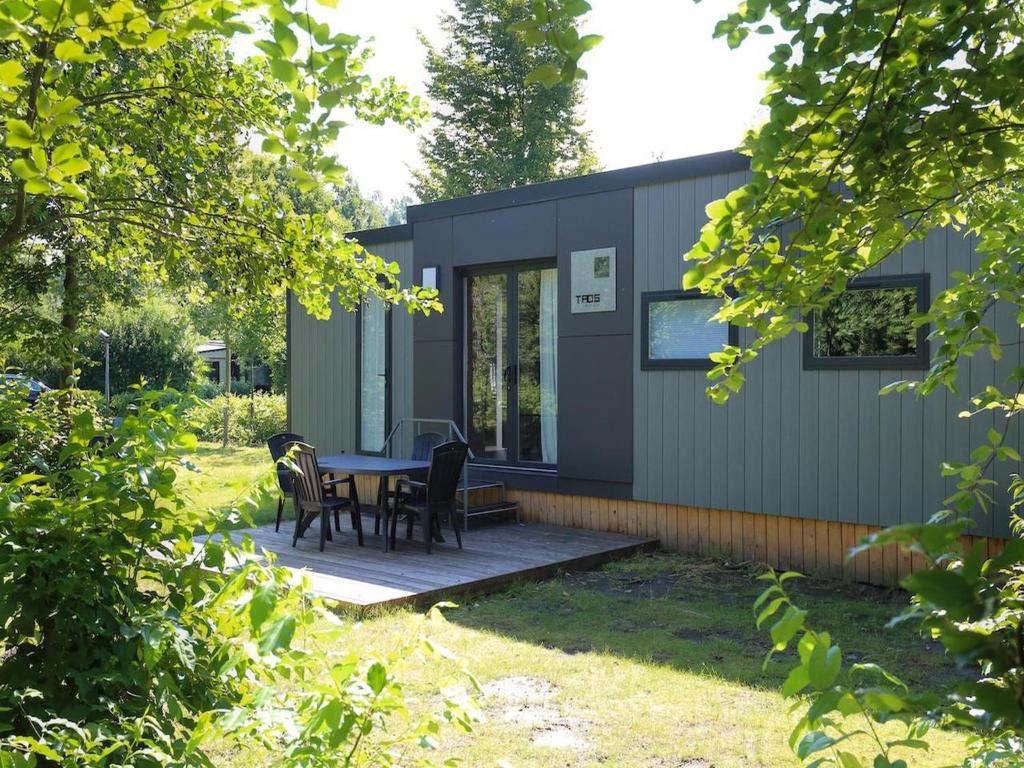 a tiny house with a table and chairs in a yard at Chalet in Baalse Hei with Modern Comforts in Turnhout