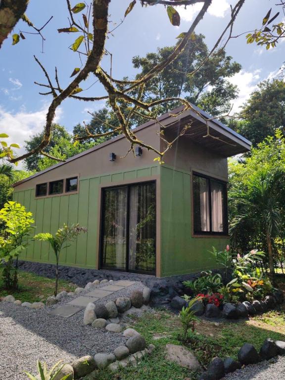 a green and white house in a garden at Secret Hideaway in Guápiles