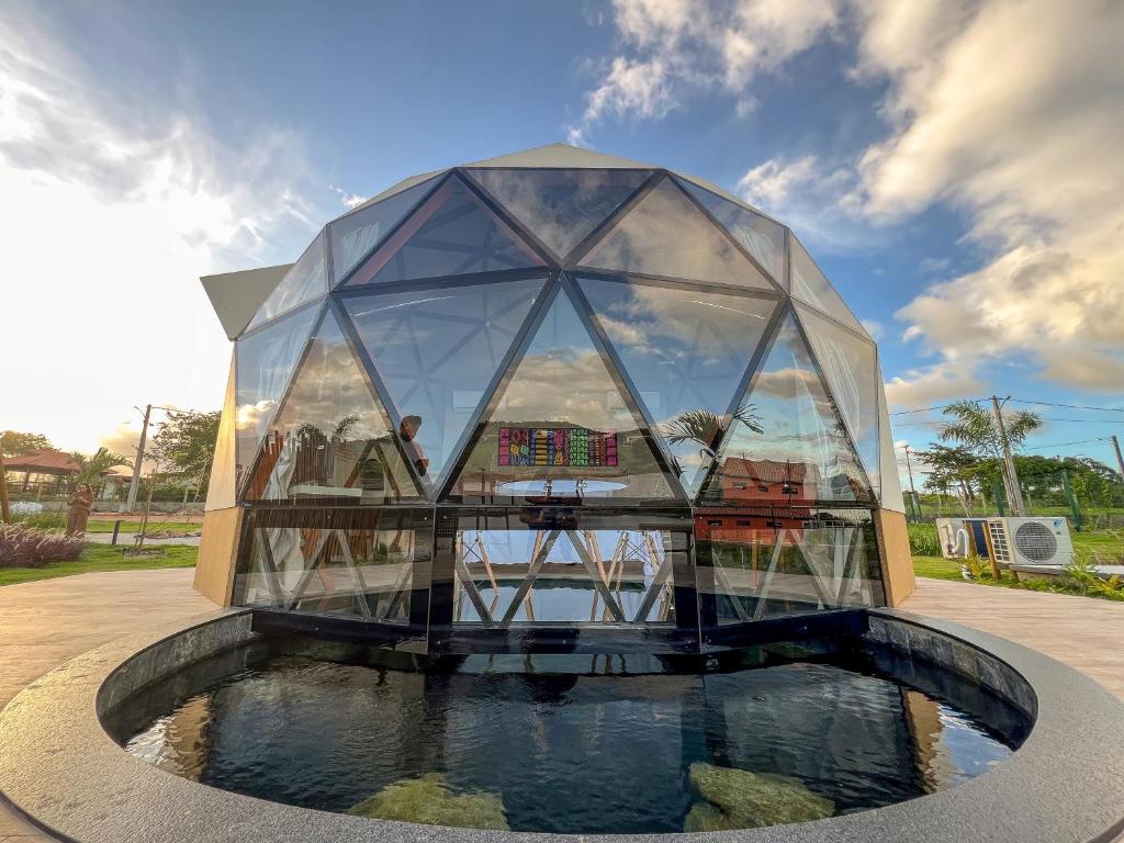 a glass house with a pond in front of it at Ville do Lago in Gravatá