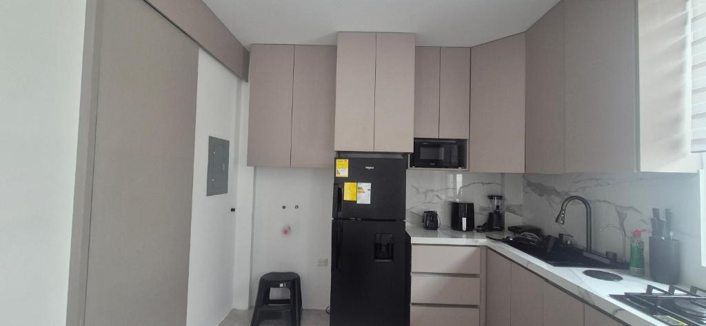 a kitchen with a black refrigerator and white cabinets at Renata's Depar in Punta Blanca