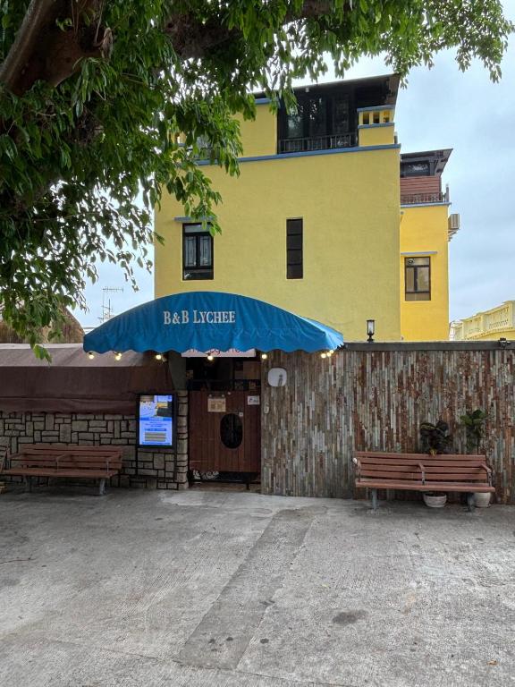 a building with a blue umbrella and two benches at B&B Lychee Sunset in Hong Kong