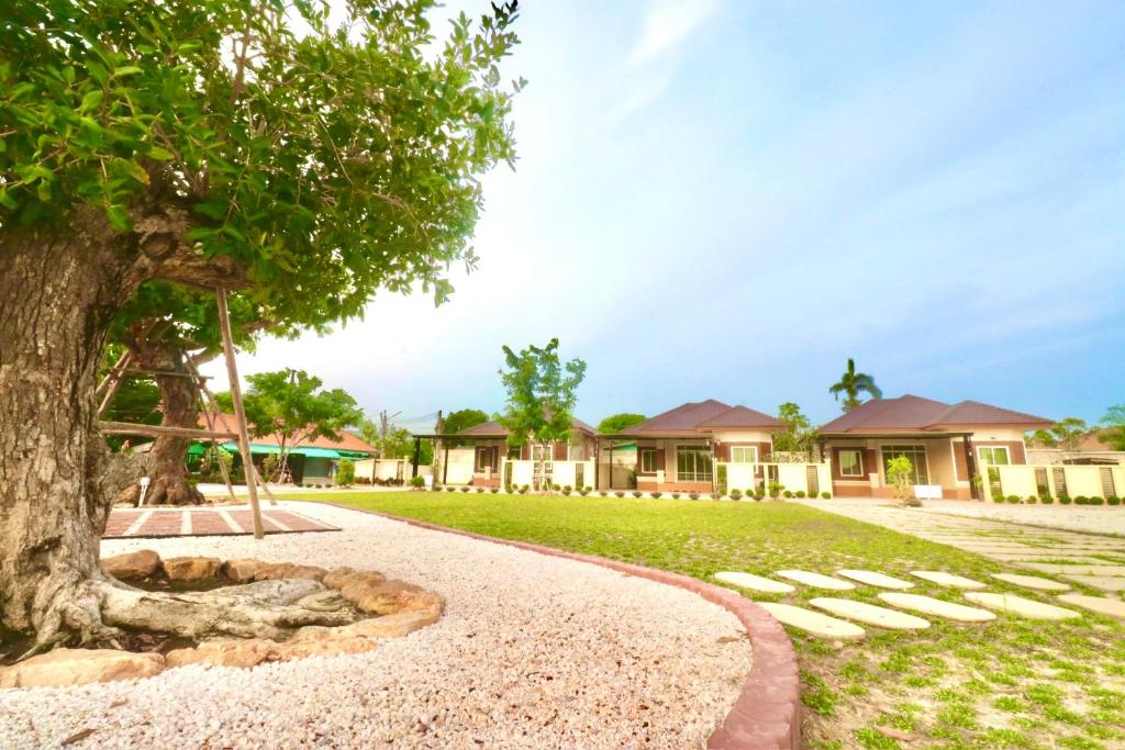 a house with a tree in front of a yard at รักแรกพบรีสอร์ทสัตหีบ in Sattahip