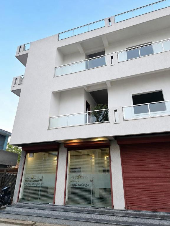 a white building with windows and a red garage at Bhagirathi Residency in Rishīkesh
