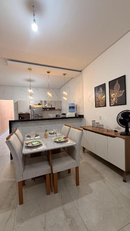 a dining room with a table and chairs and a kitchen at Casa Luxo & Conforto com 4 camas e 2 quartos completa in Juazeiro do Norte