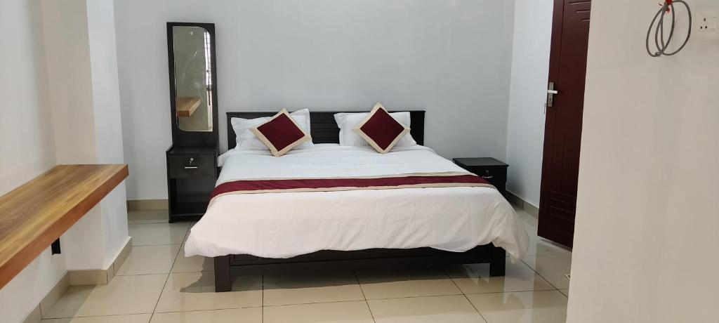 a bedroom with a bed with white sheets and pillows at Sea Breeze Residency in Kozhikode