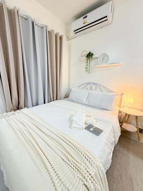 a bedroom with a white bed with a book on it at Cozy Escape Calaca in Calaca