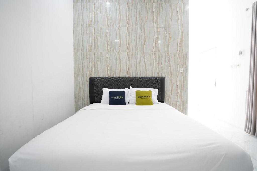a white bed with two pillows on top of it at Urbanview Hotel Nimara Ngawi by RedDoorz in Ngawi