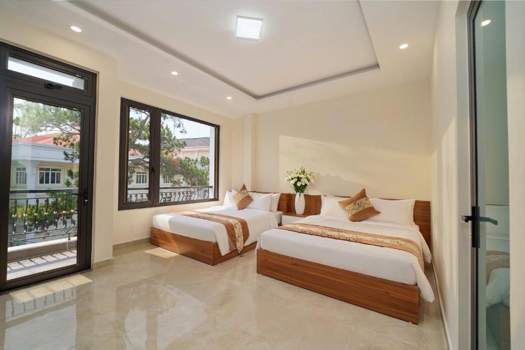 a bedroom with two beds and a large window at Hotel Duy Phương 2 in Da Lat