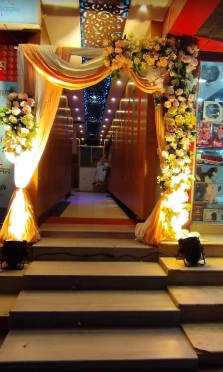 a hallway with a stage with a bunch of flowers at Hotel Relax Time in Kāmarpāra