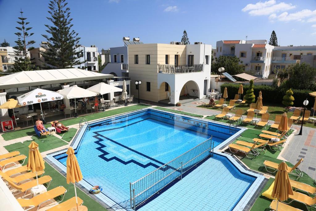 una gran piscina con sillas y sombrillas en Artemis Apartments, en Gouves