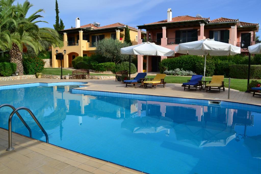 a swimming pool with chairs and umbrellas in front of a house at Nymfes Villas in Porto Heli