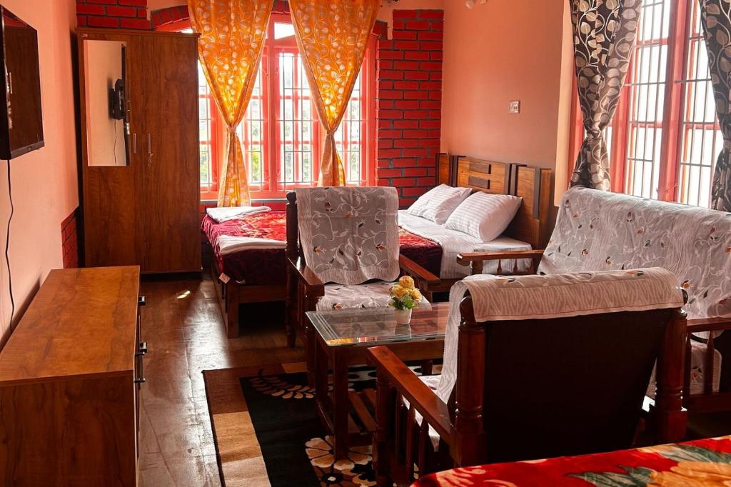 a living room with chairs and a table and windows at Kodai Mistview Cottage in Kodaikānāl
