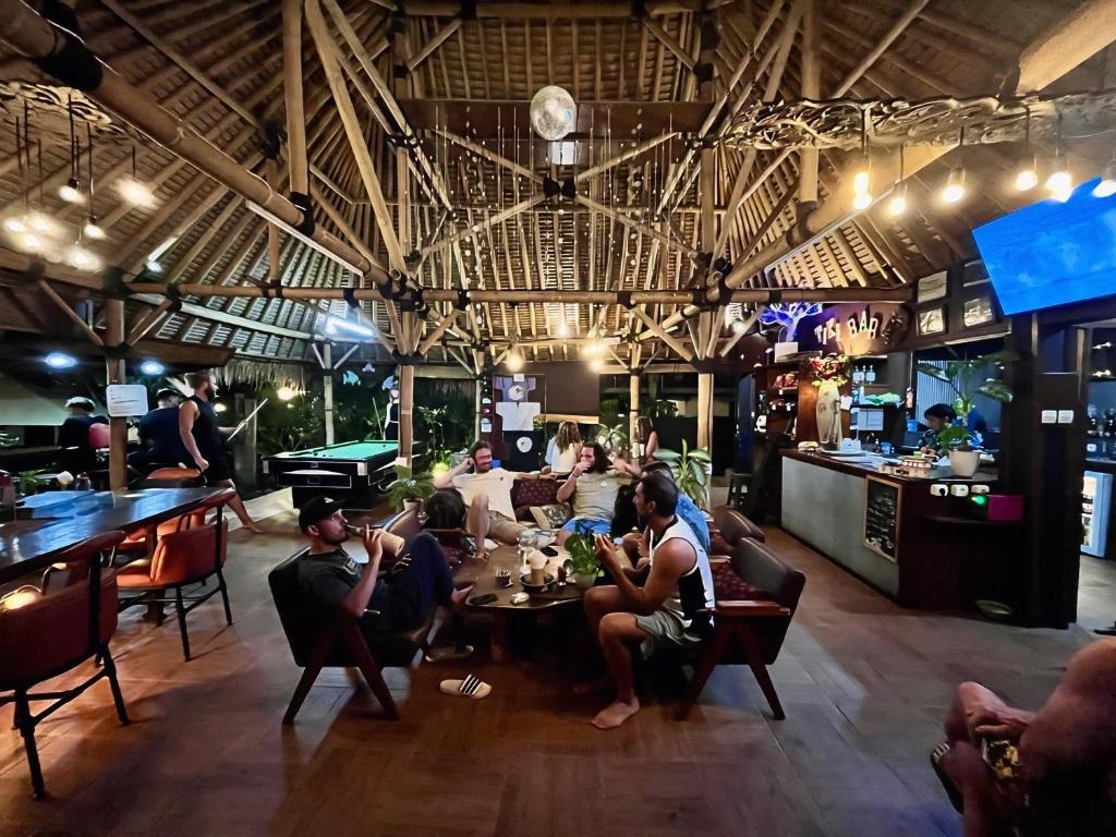 a group of people sitting at a table in a restaurant at Ombak Resort at Ekas , a luxury surf and kite destination, Close to Inside Ekas beach in Ekas