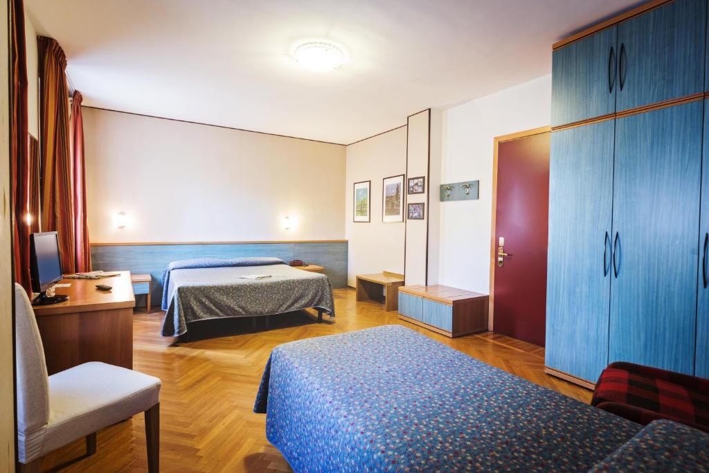 a hotel room with two beds and a chair at Hotel Roma in Aosta