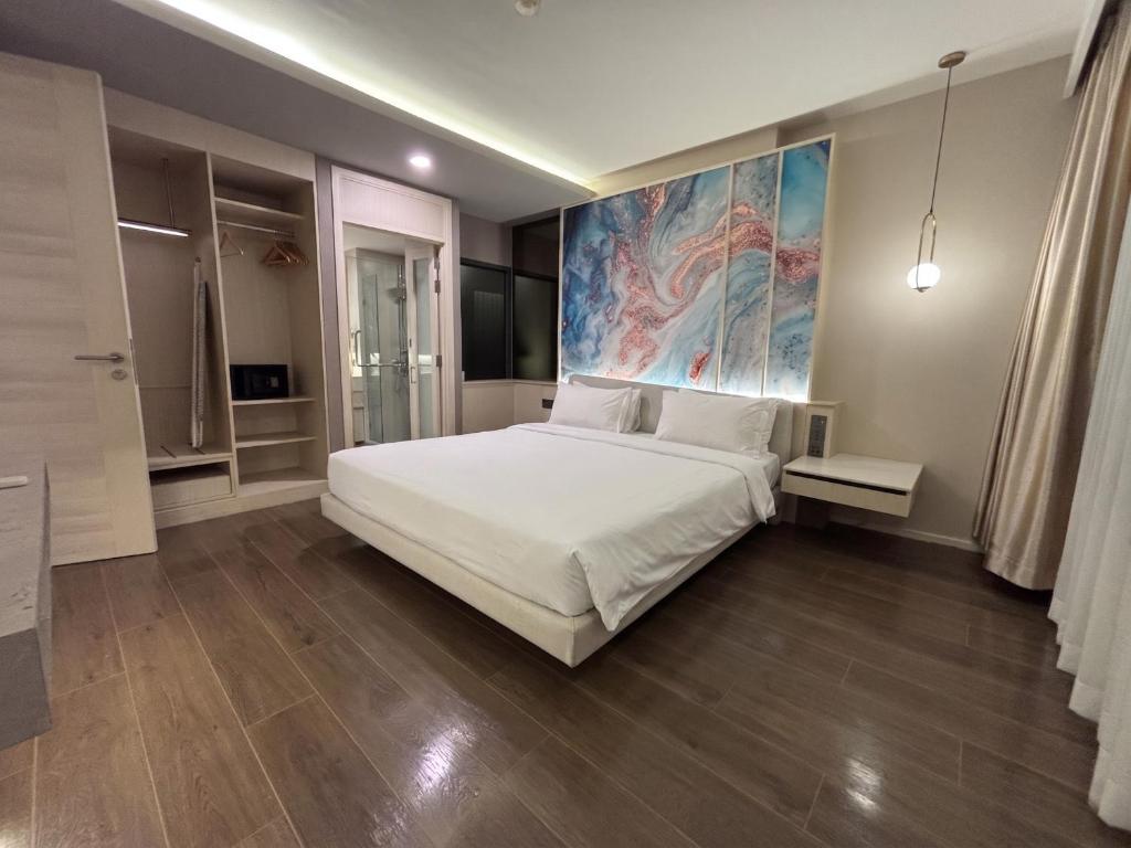 a bedroom with a white bed and a large painting on the wall at Bayphere Residence Private Beach With Fitness and Pool in Na Jomtien