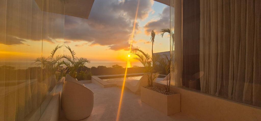 a room with a view of the ocean and the sunset at The Siren Resort Nusa Penida - Ocean View Villas in Nusa Penida