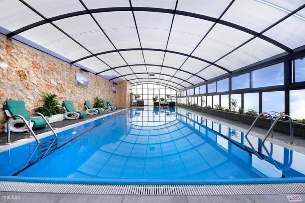 une grande piscine avec un plafond en verre dans l'établissement Achuza Bamarom, à Safed