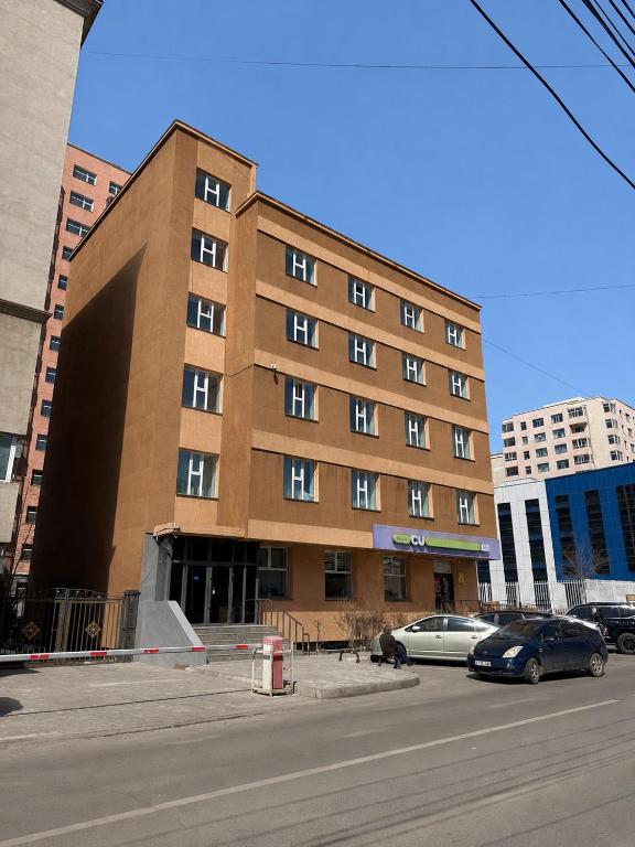 a large brown building with cars parked in front of it at Sats hotel in Ulaanbaatar