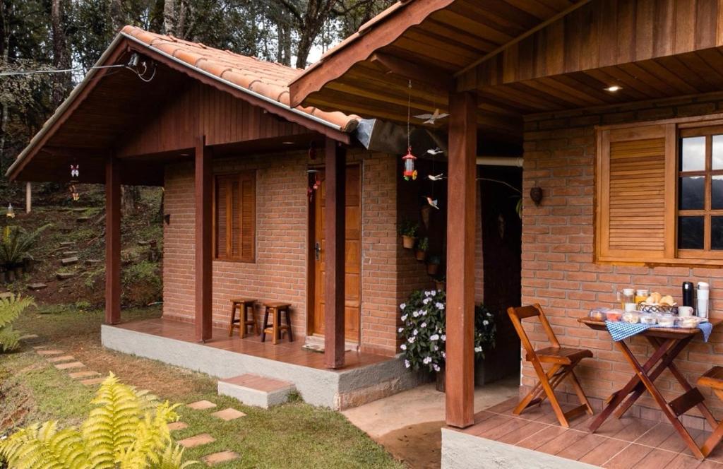 a small brick house with a table and chairs at Chalés Terra dos Sonhos - Monte Verde in Monte Verde
