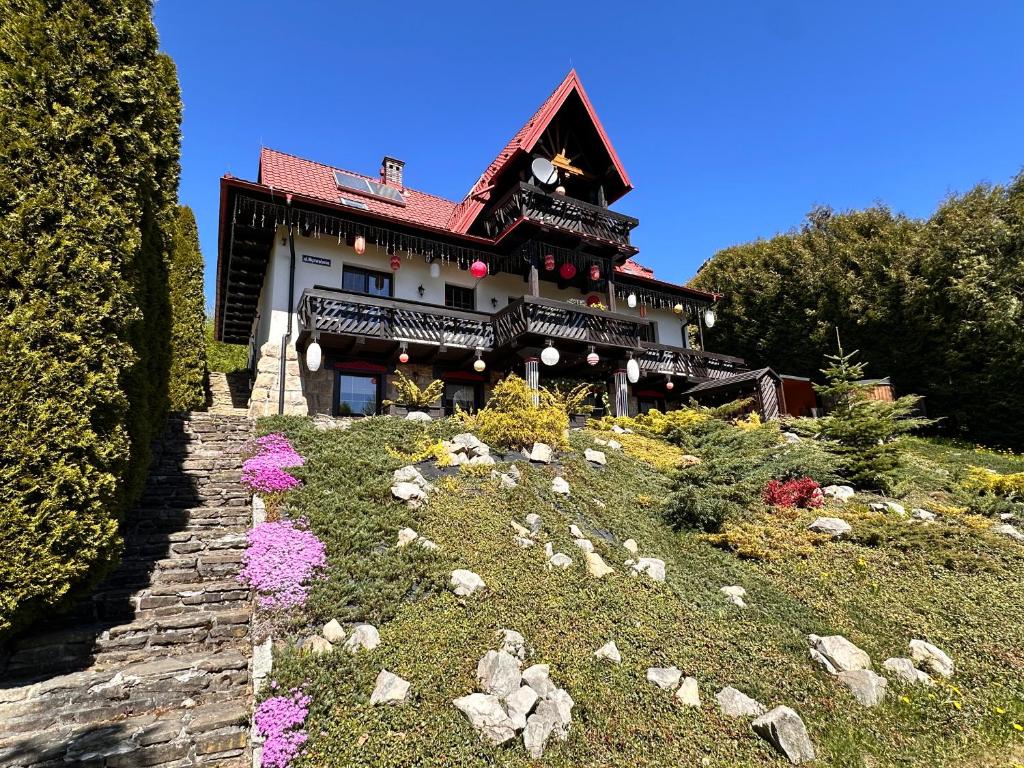 a house on a hill with flowers in front of it at Villa Good Time in Wisła