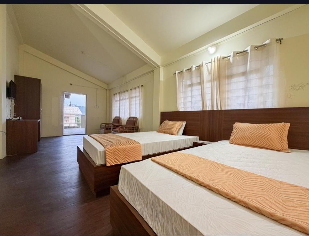 a bedroom with two beds and a chair in it at Green View Bungalow in Shillong