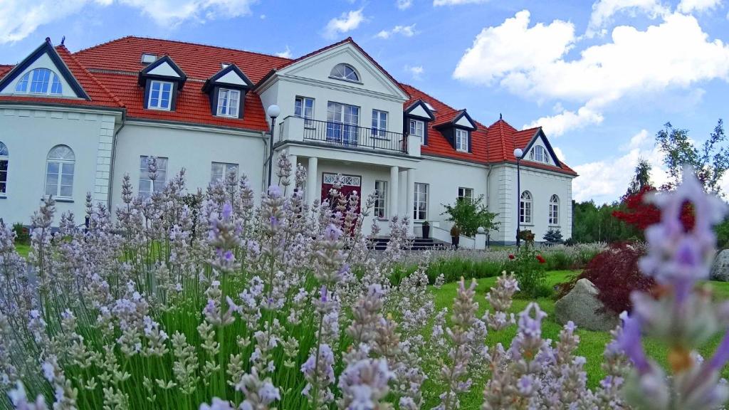 White country mansion framed by lavender flowers in the foreground and landscaped gardens.