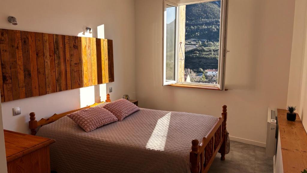 a bedroom with a bed with a large window at La Belle Vue - Gîte 3 étoiles Eco Responsable Climatisé in Maury
