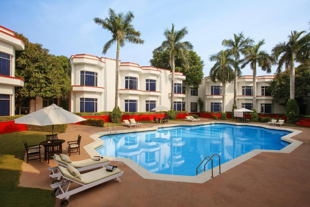 a hotel with a pool and chairs and palm trees at Ramada Khajuraho in Khajurāho