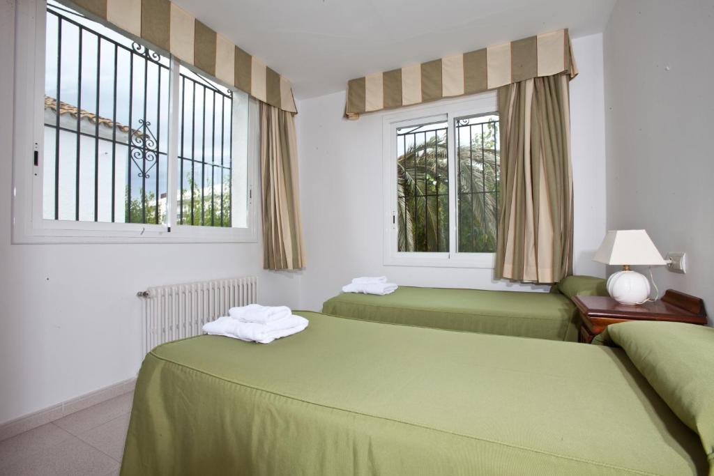 2 grüne Betten in einem Zimmer mit 2 Fenstern in der Unterkunft Sunway Torre La Veleta in Sitges