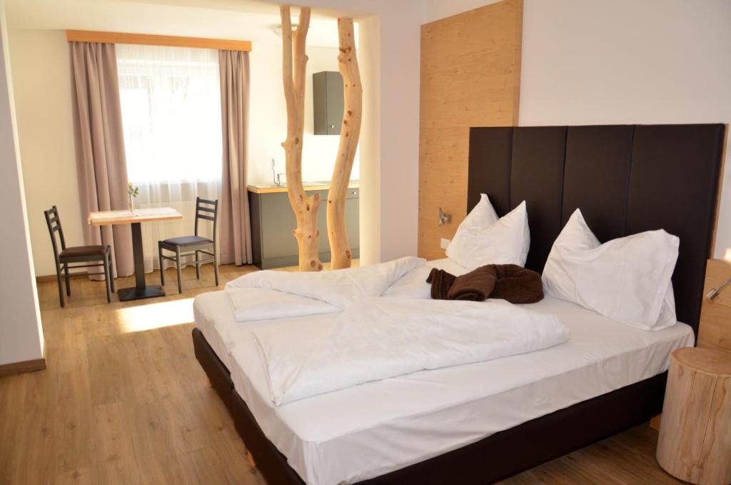 Schlafzimmer mit einem großen weißen Bett mit einem Kopfteil aus Holz in der Unterkunft Guesthouse Dolomiten in Neumarkt