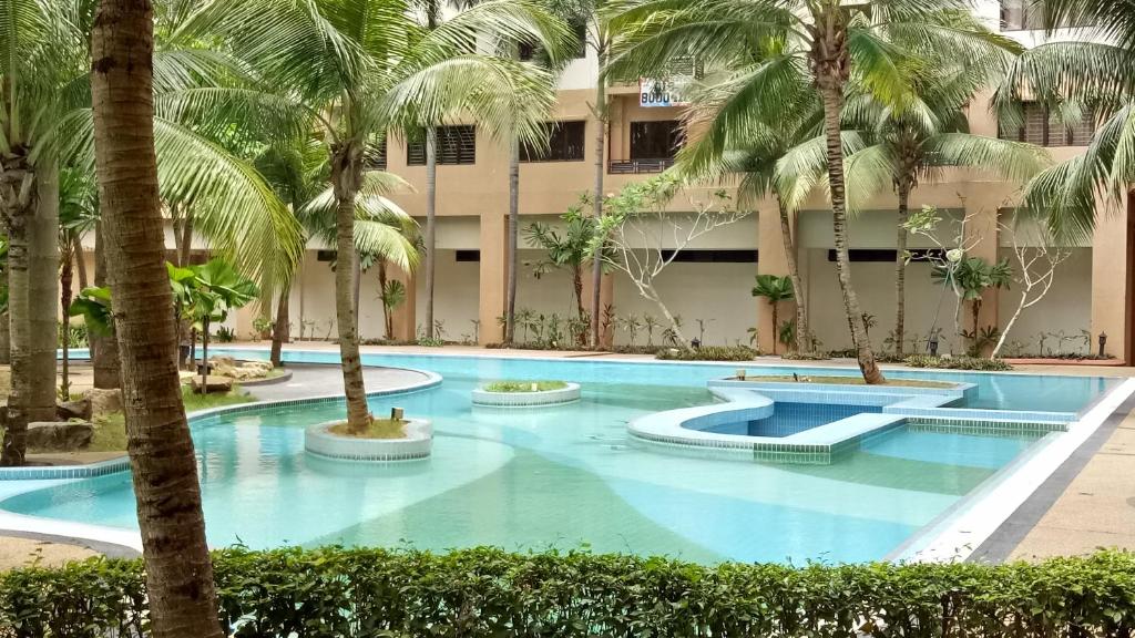 a large swimming pool with palm trees in front of a building at DKajang Villa Homestay Kajang in Kajang