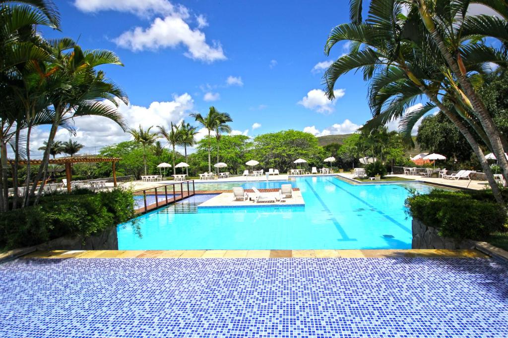 uma piscina num resort com palmeiras em Portal de Gravatá em Gravatá