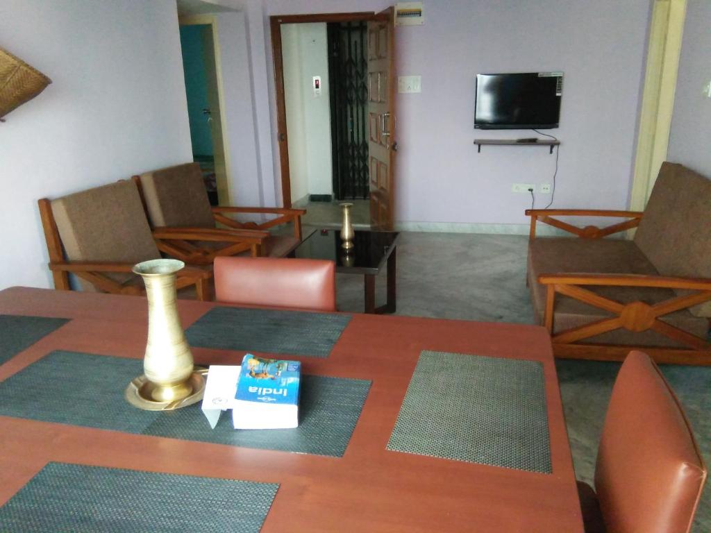 sala de estar con mesa, sillas y TV en Nalanda Tulip en Calcuta
