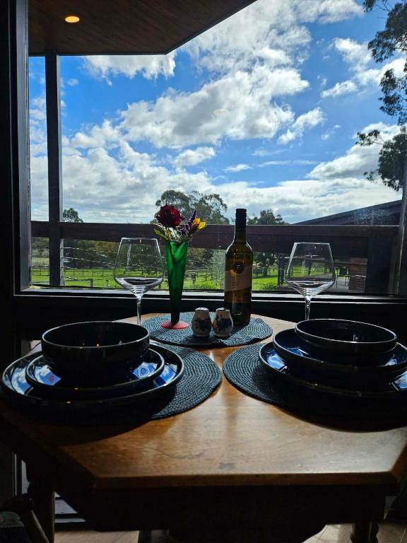 a table with plates and wine glasses and a window at Hill Top Park - Apple Tree Studio in Kilmore
