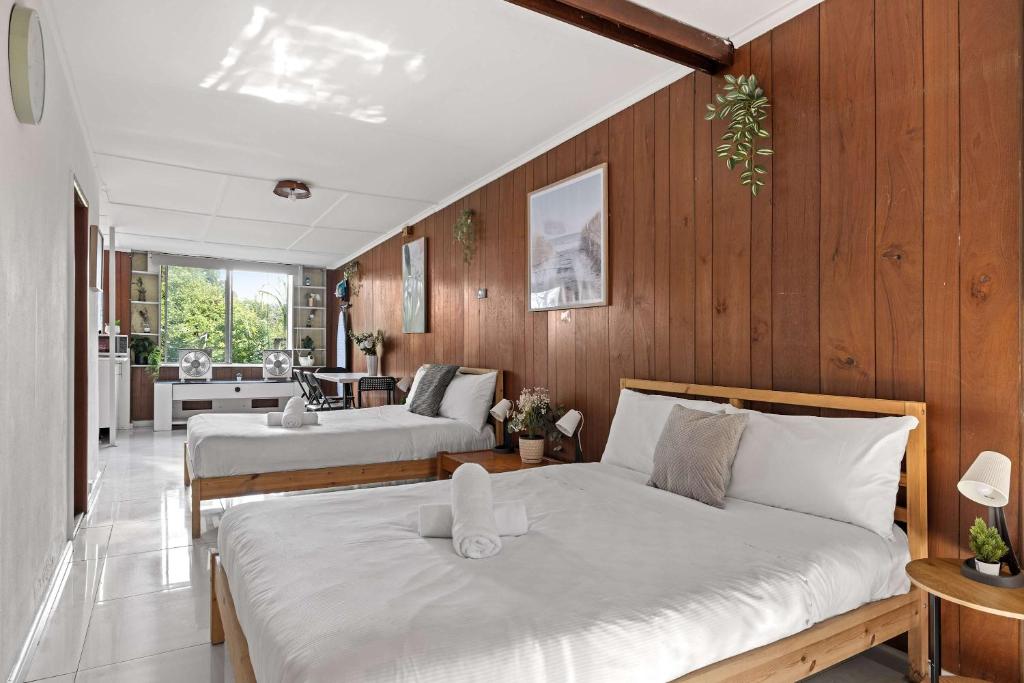 two beds in a room with wooden walls at Simple 2-Double Bed Studio Stay at Peakhurst in Peakhurst