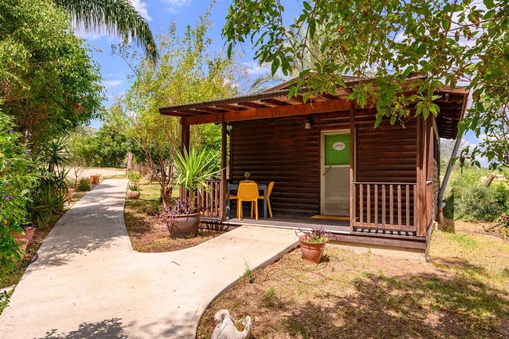 a small wooden cabin with a table and a chair at בינות התמרים- 3 צימרים מהממים עם בריכה וג'קוזי ספא! in Menaẖemya