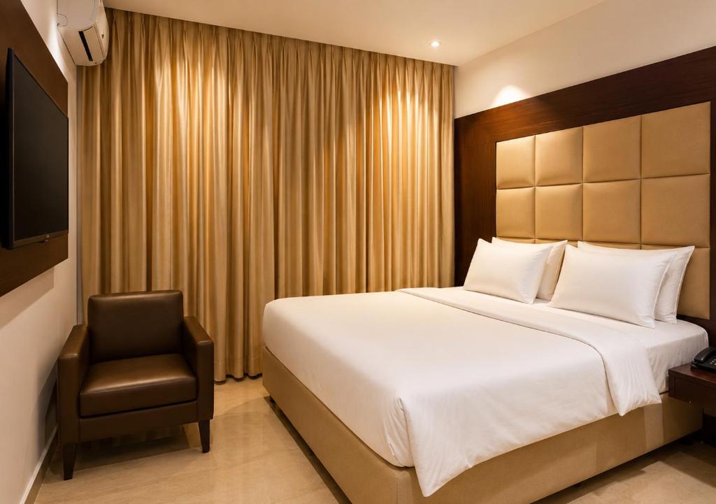 a hotel room with a bed and a chair at The Savannah Hotel, Garki in Abuja