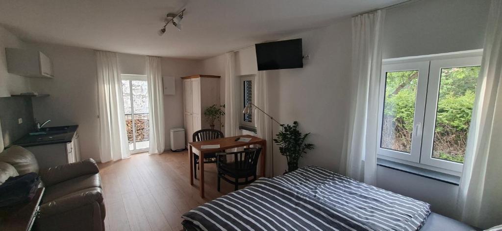 a bedroom with a bed and a table and a room with a couch at Apartments Leipziger Neuseenland in Markkleeberg