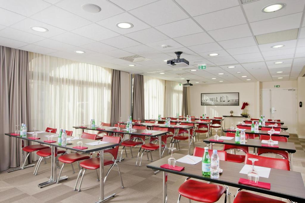 a dining room with tables and red chairs at Residhome Arcachon Plazza in Arcachon