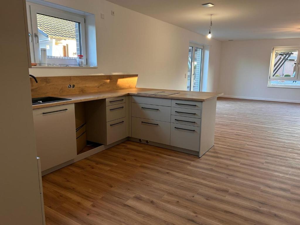 an empty kitchen with white cabinets and a wooden floor at Ferienwohnung- Monteurwohnung Diepholz in Diepholz
