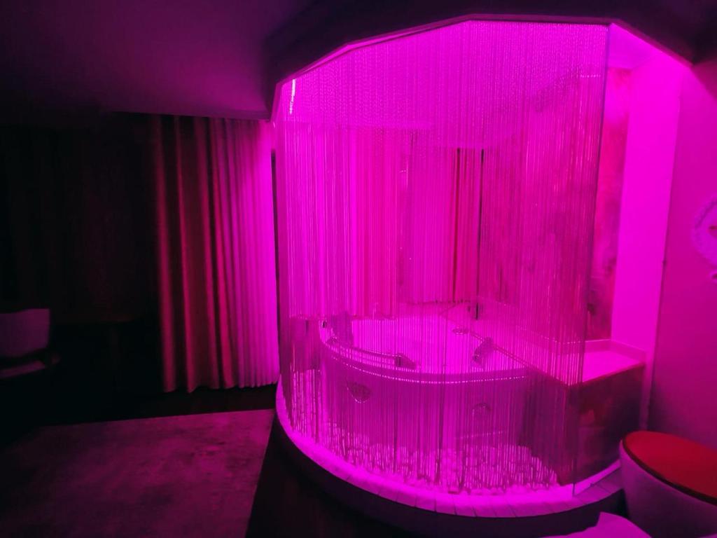 a bathroom with a pink lighted tub in a room at Hotel Rosa Blu in Tirana