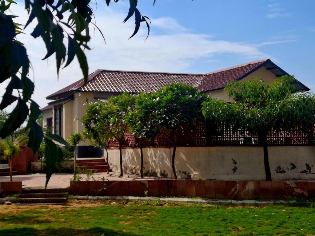 a house with a fence and trees in front of it at Raghuvan Farm in Jaipur