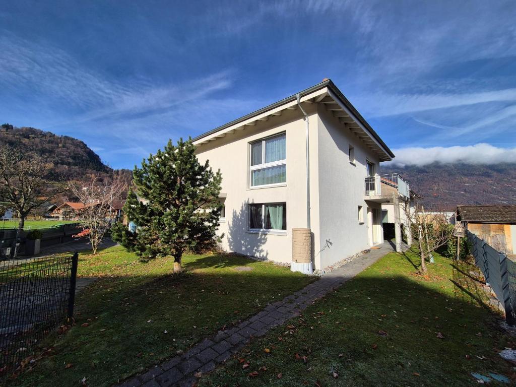 a white house with a tree in the yard at Alpine Bliss Studio in Wilderswil