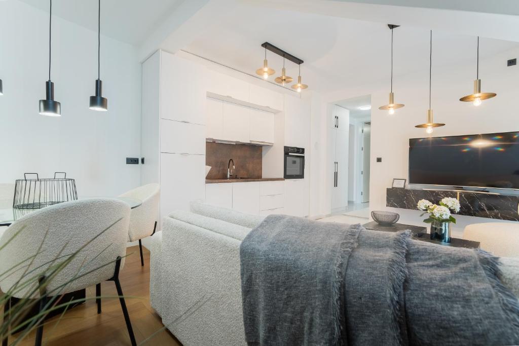 a white living room with a couch and a table at Liberty Central Apartment in Tuzla