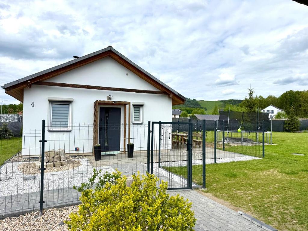 a small white house behind a fence at Chabrowy Domek in Jeżów Sudecki