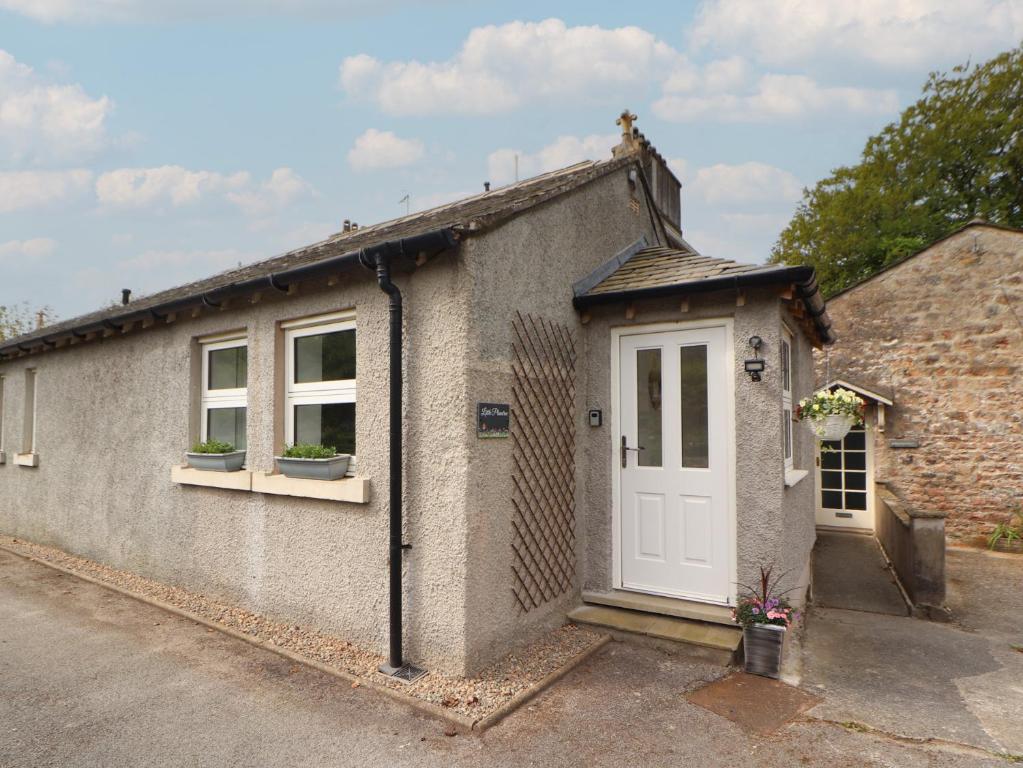a brick house with a white door and windows at Little Plumtree in Milnthorpe