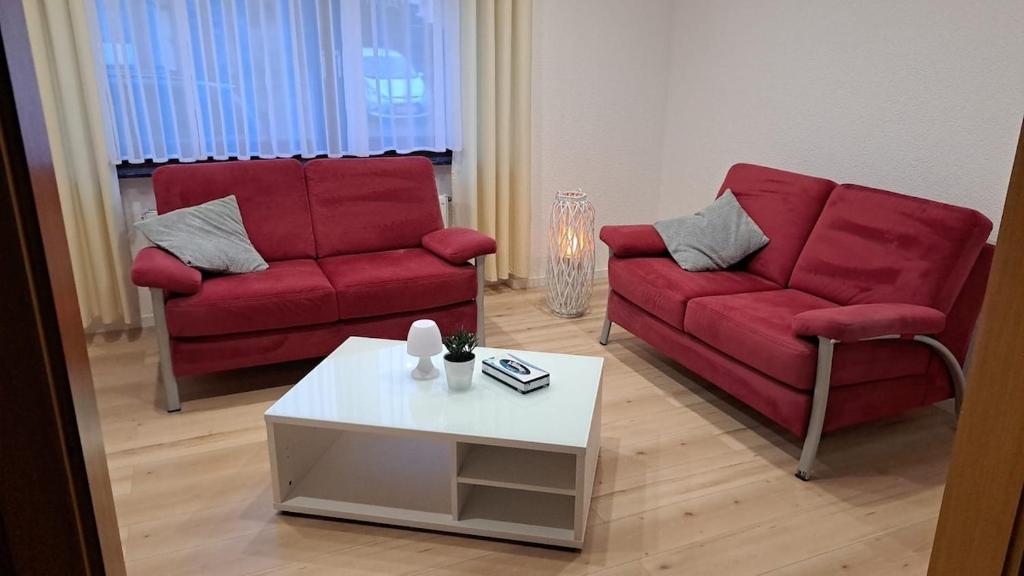 a living room with two red couches and a coffee table at Haus Linde in Wengenroth