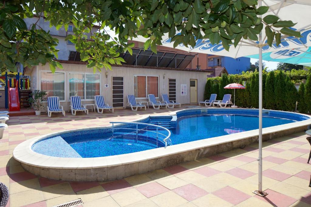 a large swimming pool with chairs and an umbrella at Peshev Family Hotel Nesebar in Nesebar